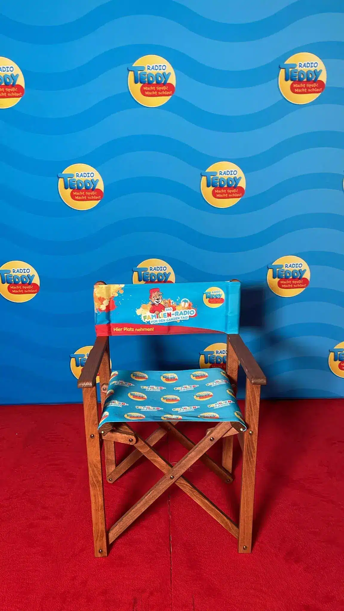 Der Klappstuhl steht vor einer Radio TEDDY-Fotowand